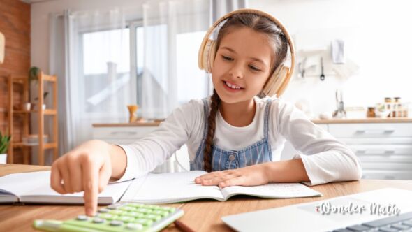 Picture of young girl doing math with her calculator and text books with headphones on.