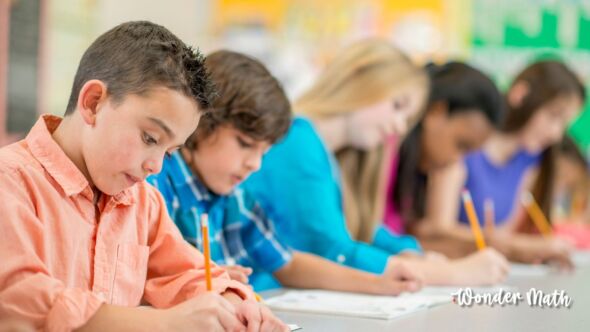 Multiple young students taking a test in a classroom.