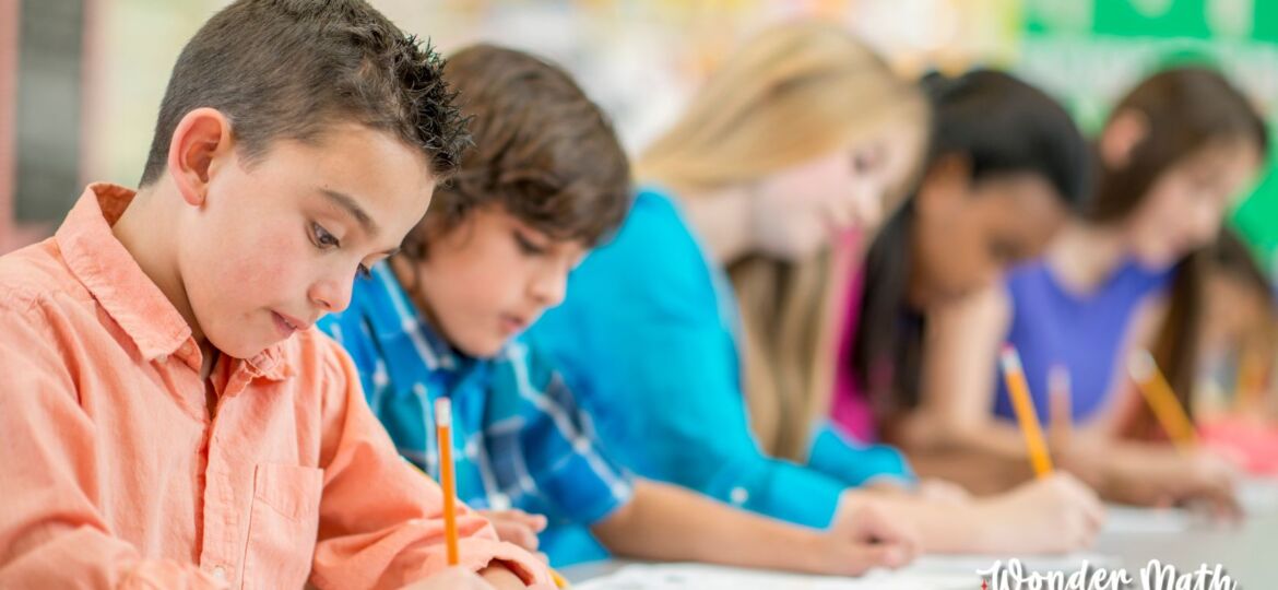 Multiple young students taking a test in a classroom.
